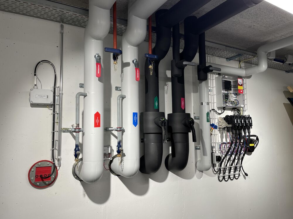 Gebäude-Einführungen: Datenübertragung Fernwärme, VL/RL Fernwärme, VL/RL Fernkälte, Trinkwasser. Rechts: 5 Mikro-Wechselrichter zu Solar-Gehwegplatten.